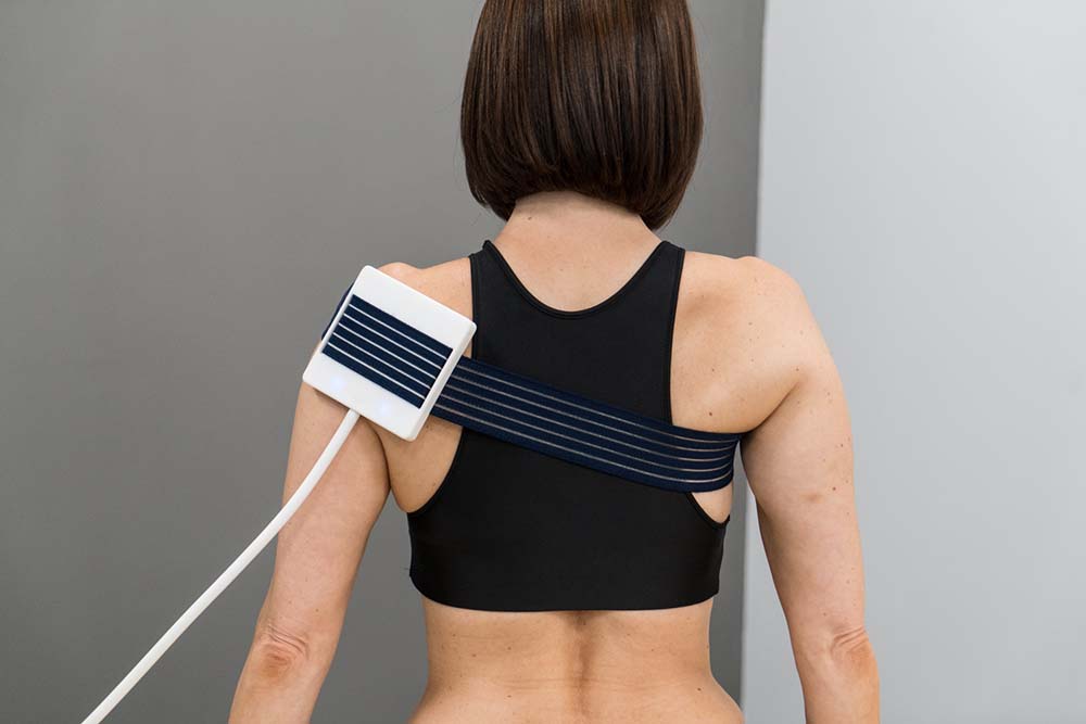 Una donna di spalle, con il dispositivo Cerc Therapy in fase di trattamento di una spalla